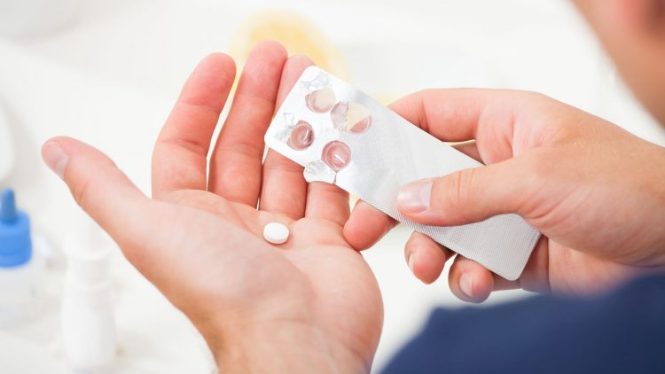 Mensch drückt Tabletten aus Blisterverpackung