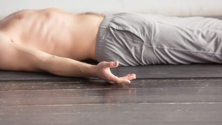 Mann liegt mit nacktem Oberkörper auf dem Boden